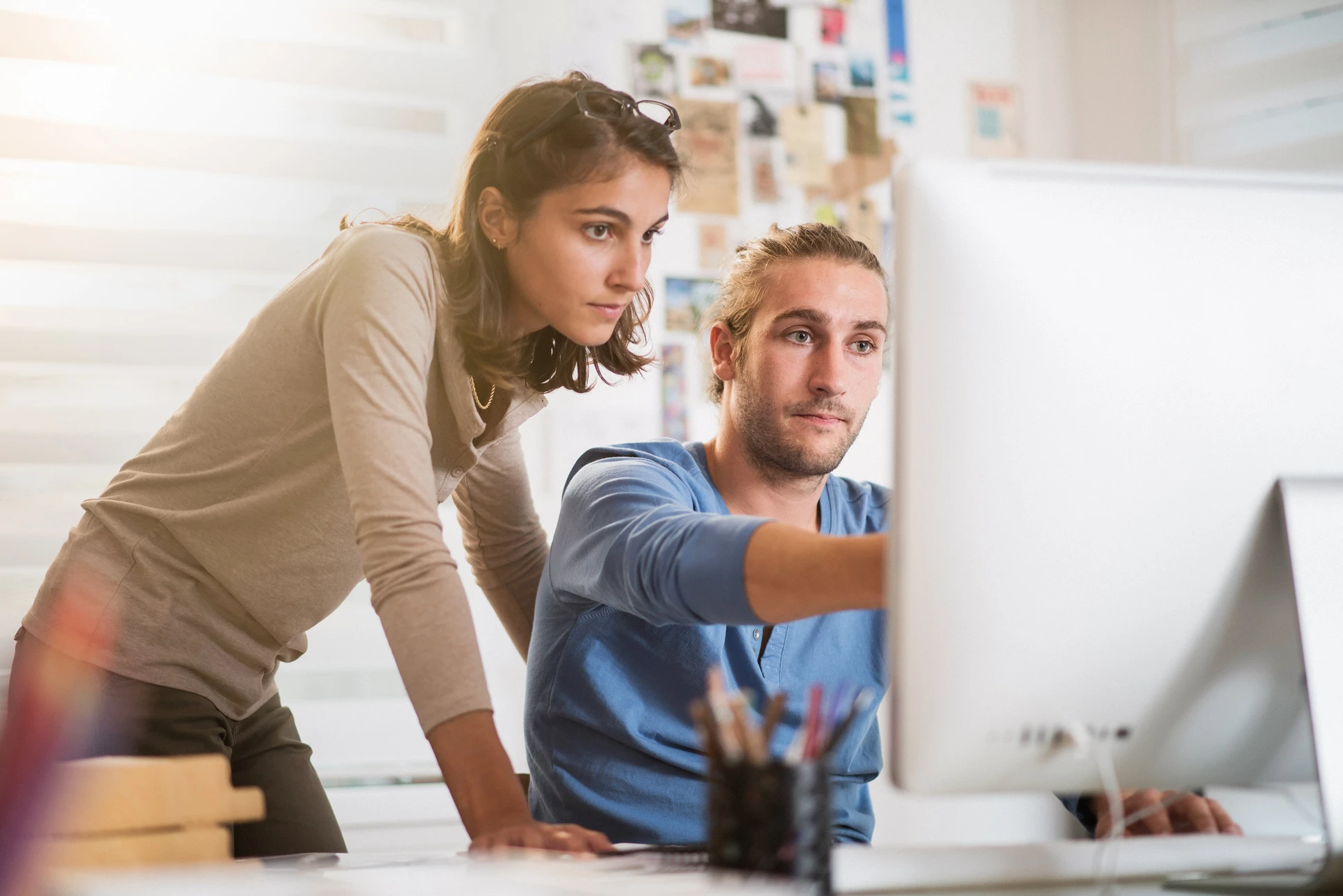 Une femme et un homme collaborent devant un ordinateur dans un bureau moderne
