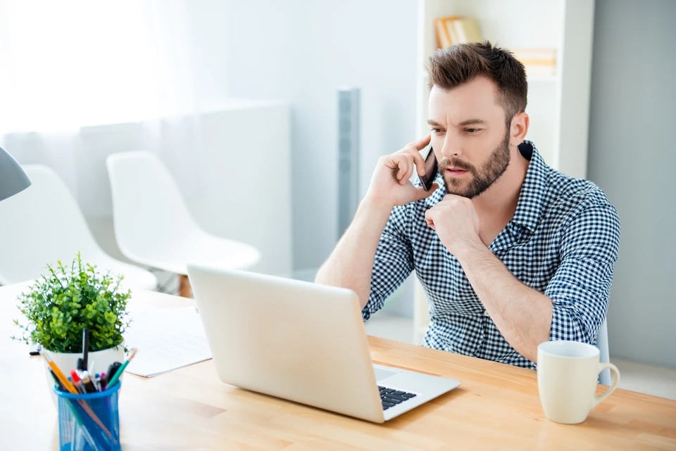 Un beau homme d'affaires concentré parlant sur un téléphone portable au bureau