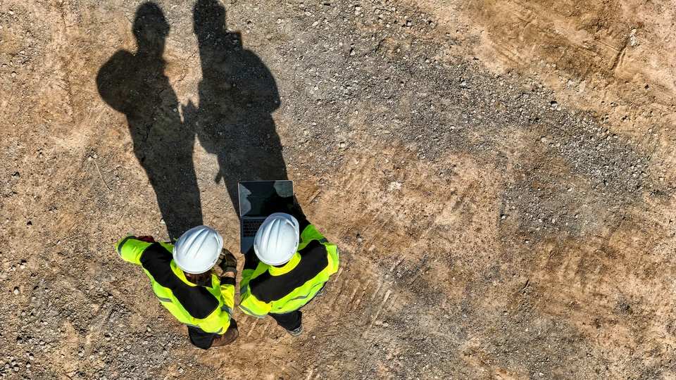 Ouvrier du bâtiment souriant en salopette bleue et casque de sécurité dans un entrepôt de matériaux de construction