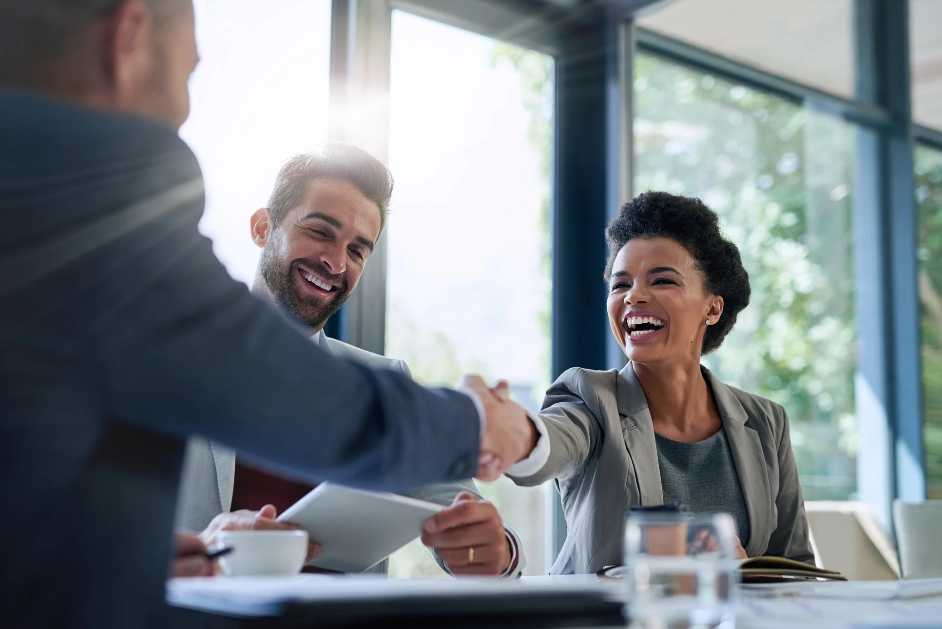 Un consultant en ressources humaines en entretien avec un candidat dans un bureau moderne et accueillant, tous deux assis dans un environnement bienveillant, engagés dans une conversation professionnelle constructive. Le consultant prend des notes ou consulte des documents tout en écoutant attentivement le candidat, illustrant ainsi l'accompagnement individualisé et la relation personnalisée que propose Smart Emploi.